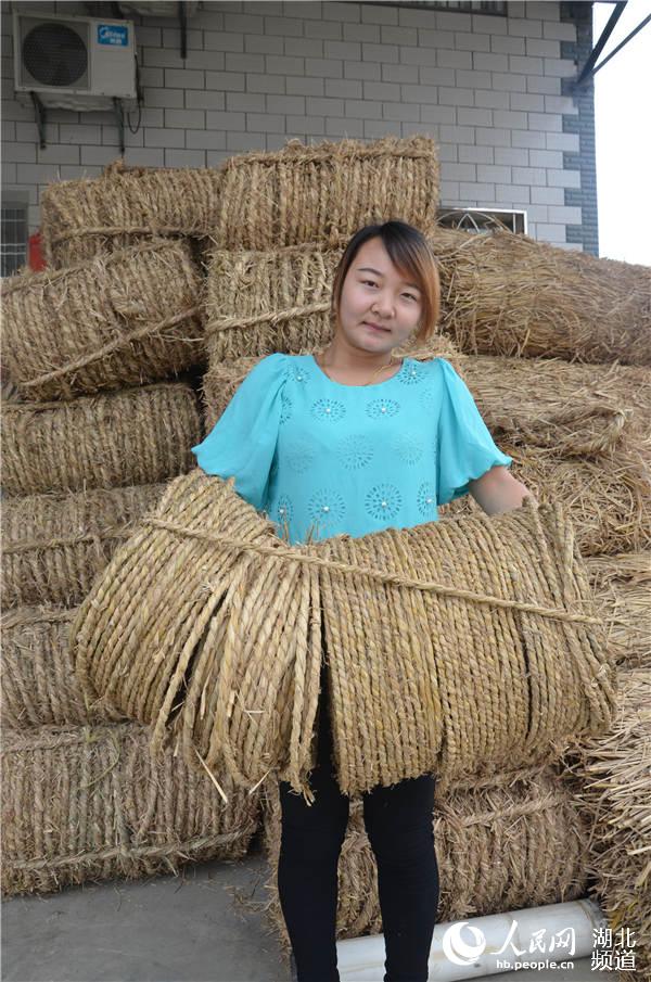 稻草加工戶曉月月為客商抱草繩上車。